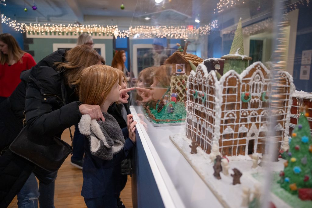 An adult points out a detail in a gingerbread creation at the Erie Canal Museum's Gingerbread Gallery.